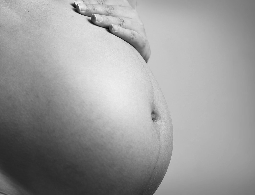 A doula's hand rests in steady support.